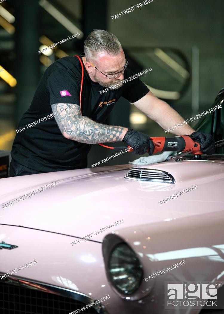 Stock Photo: 07 March 2019, Baden-Wuerttemberg, Stuttgart: An employee polishes an old Ford Thunderbird on the exhibition floor of the Retro Classics 2019 classic car fair.
