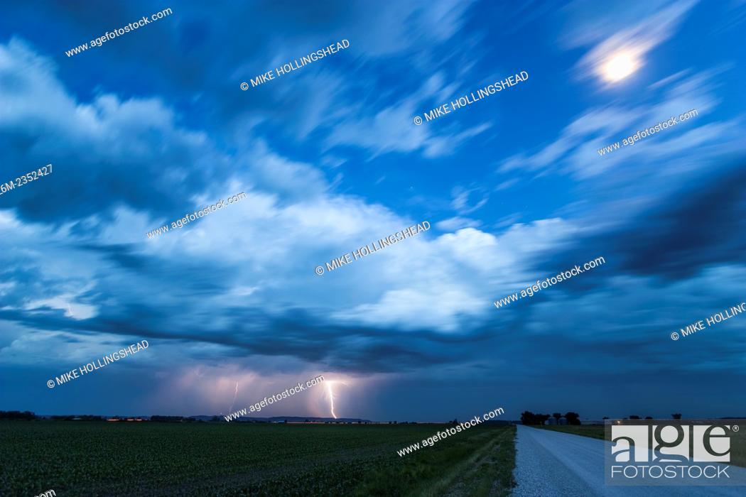Stock Photo: Lightning hits the ground in southwest Iowa as the moon shines brightly under twilight conditions.