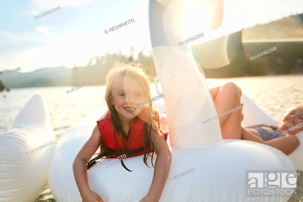 Imagen: Girls playing on inflatable swan in lake.
