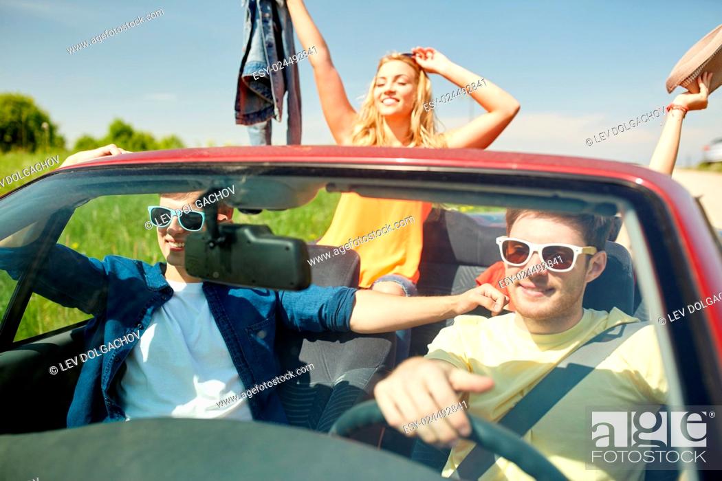 Stock Photo: leisure, road trip, travel and people concept - happy friends driving in cabriolet car along country road.
