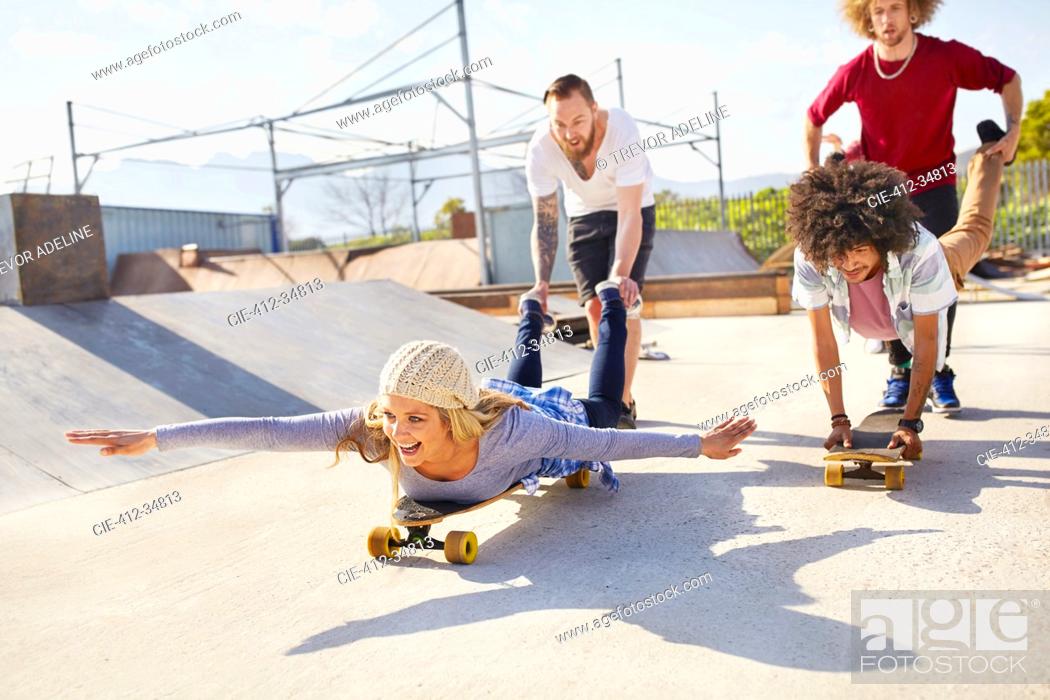 Stock Photo: Playful friends on skateboards at sunny skate park.