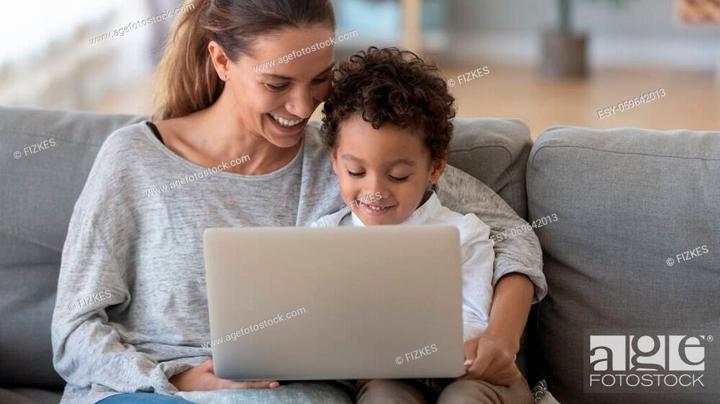 Stock Photo: Smiling mother with African American son using laptop close up, happy mum and preschool child sitting on sofa at home, watching cartoons online or play video.