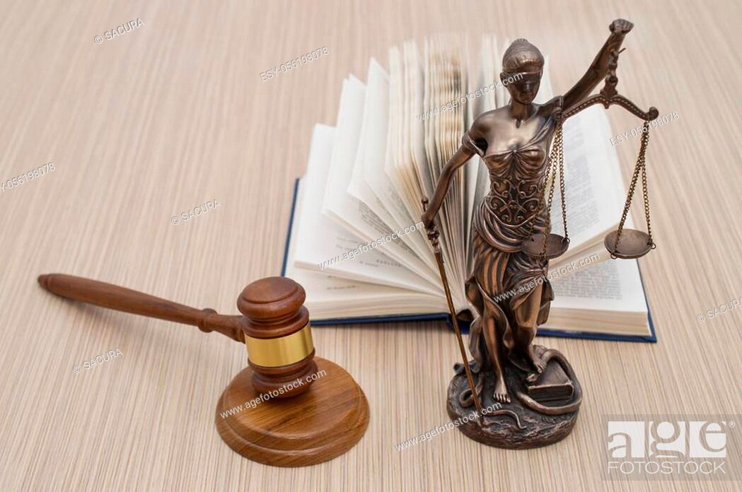 Stock Photo: statue of justice on wooden table against the background of an open book.