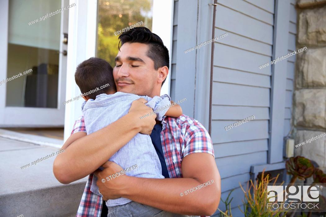 Stock Photo: Father Hugging Son Sitting On Steps Outside Home.