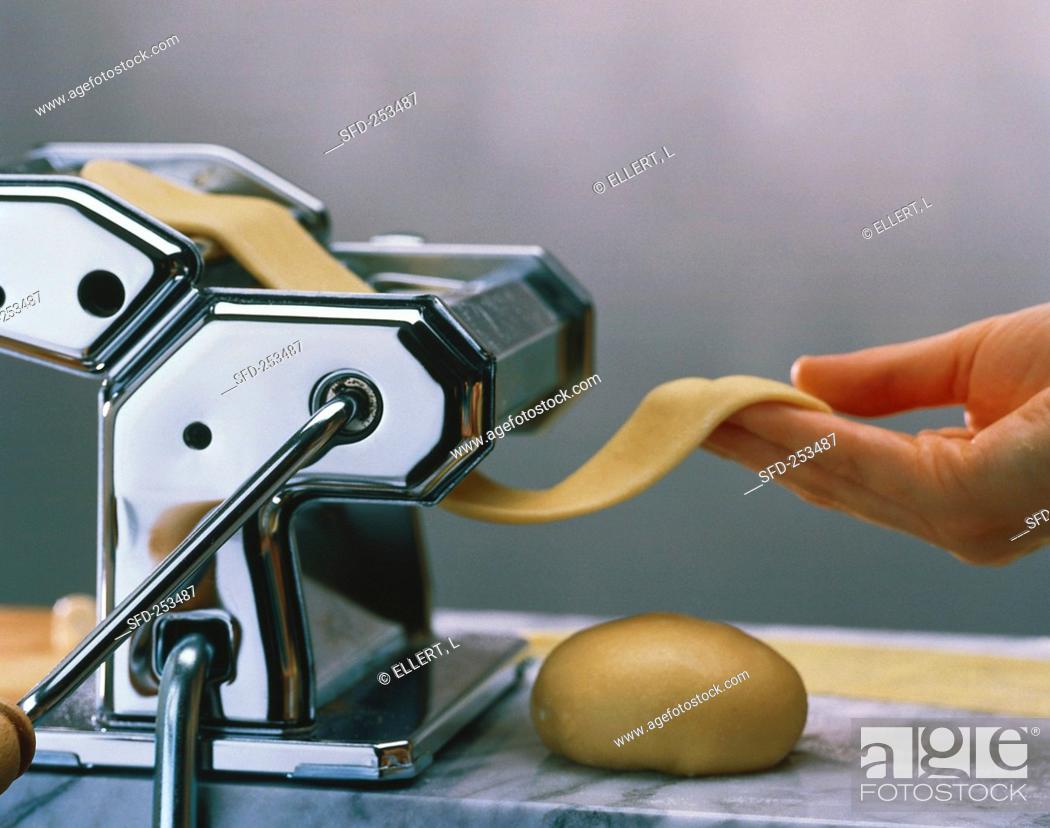 Stock Photo: Making pasta: pulling the dough through the pasta maker.