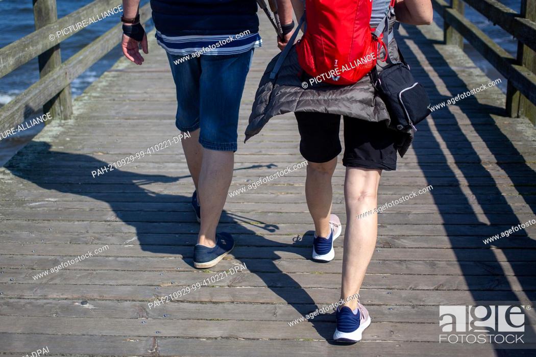 Stock Photo: PRODUCTION - 28 September 2021, Mecklenburg-Western Pomerania, Ahlbeck: A couple walks along the pier on the beach of the Baltic resort of Ahlbeck on the island.