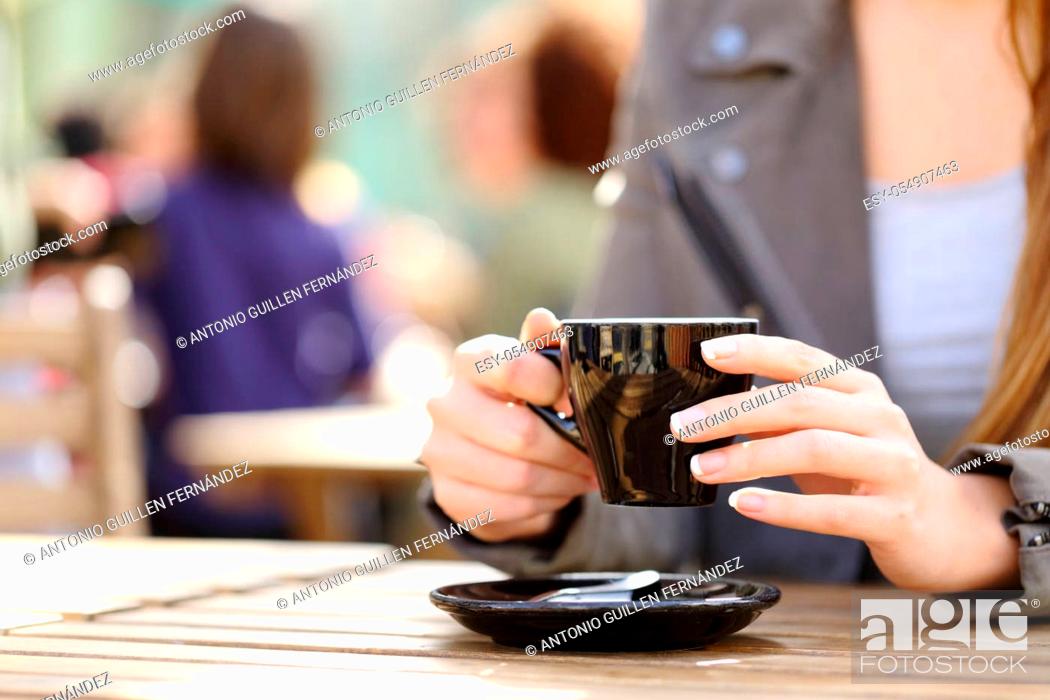 Stock Photo: Close up of a woman hands holding a coffee cup on a cafe terrace.