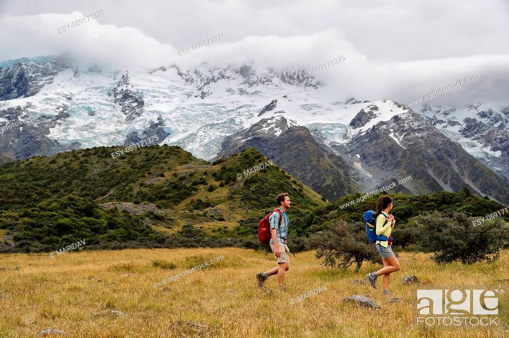 Stock Photo: New Zealand travel hikers hiking on snow capped mountains landscape background. Couple trampers walking on Hooker Valley Track.