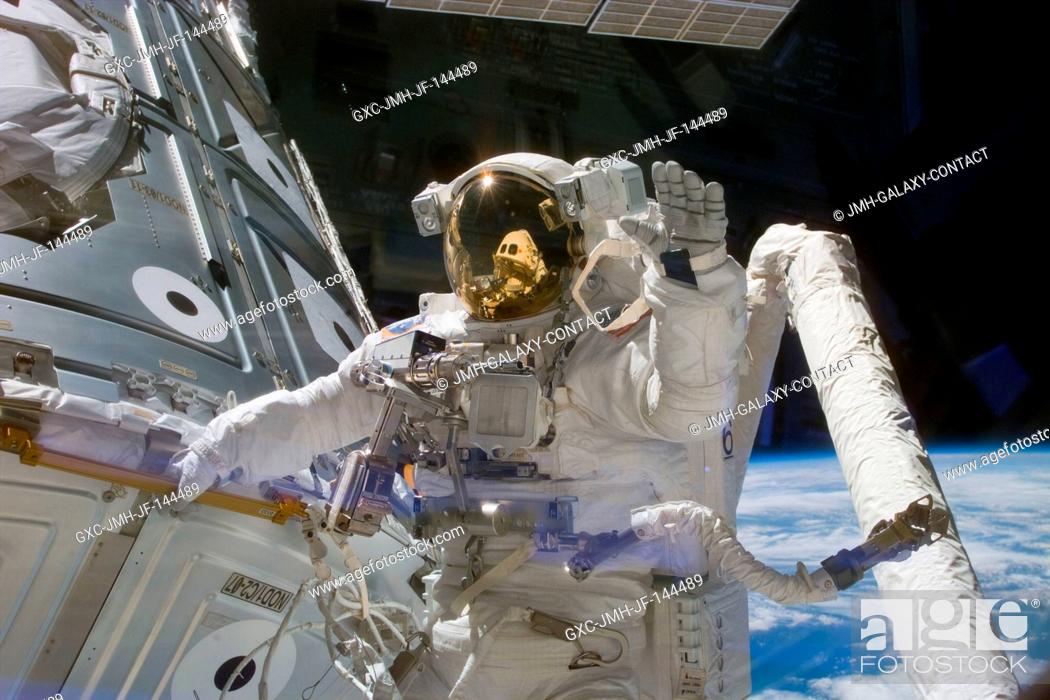 Stock Photo: Astronaut James H. Newman, waves at camera as he holds onto one of the hand rails on the Unity connecting module during the early stages of a 7-hour.
