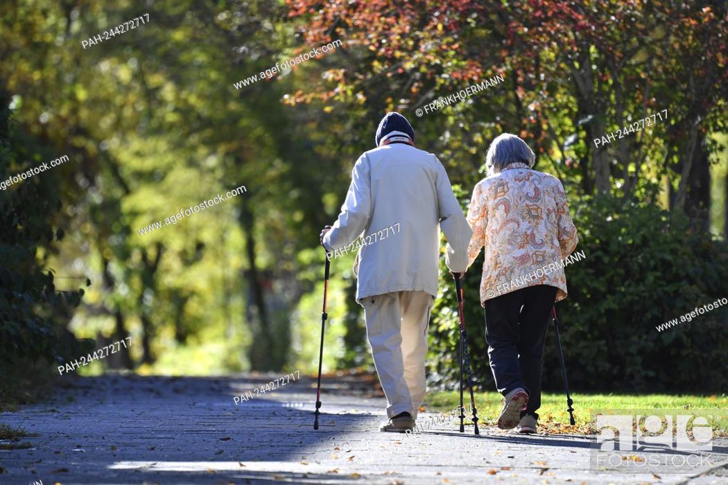 Stock Photo: Subject picture: PENSION AT 68 Archive photo: old married couple pensioners man and woman go for a walk with Nordic walking sticks.