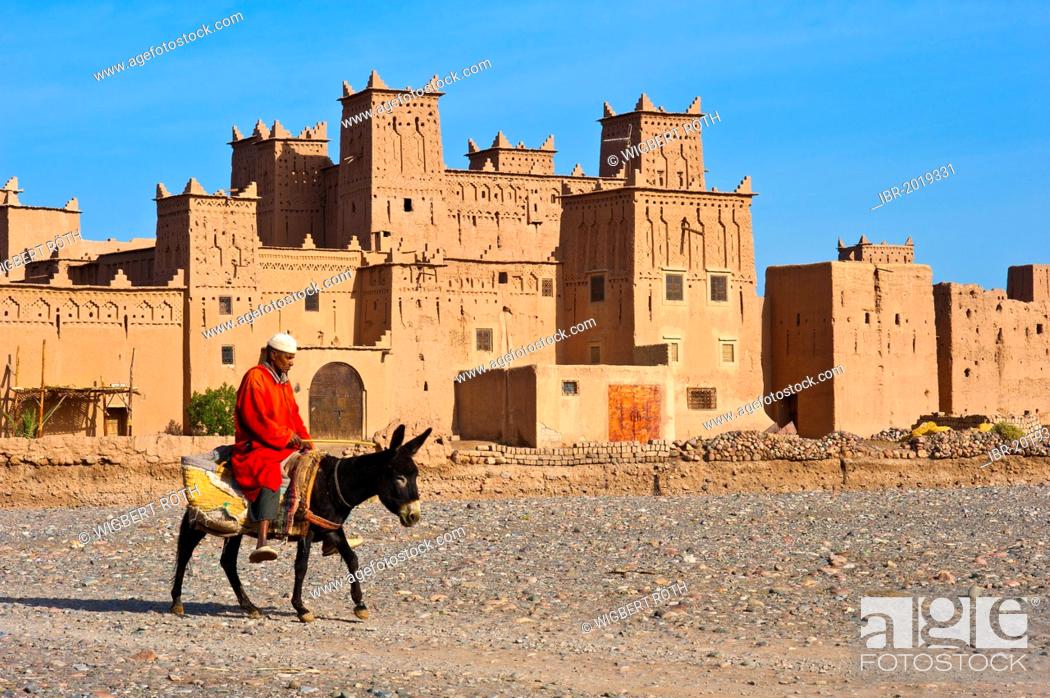 Stock Photo: Berber riding on a donkey in front of the Amerhidil Kasbah, mud fortress, residential Berber castle, Tighremt, Skoura, Dades Valley, southern Morocco, Morocco.