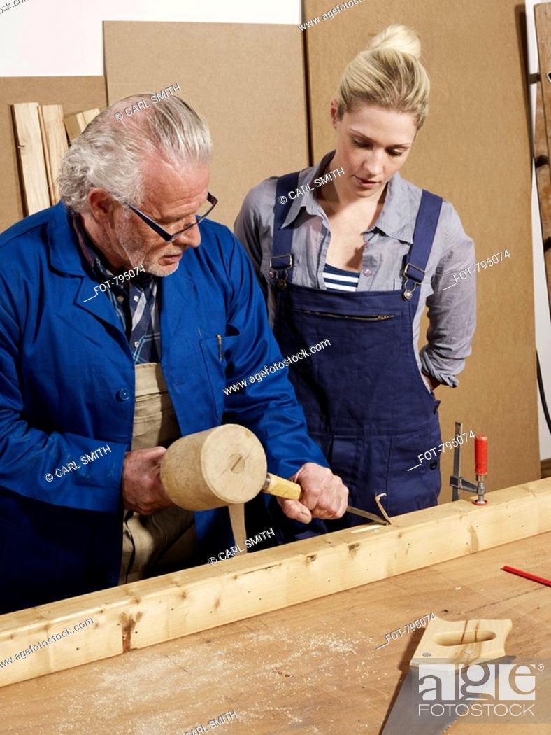 Stock Photo: A man demonstrating wood chiseling to a woman in a workshop.