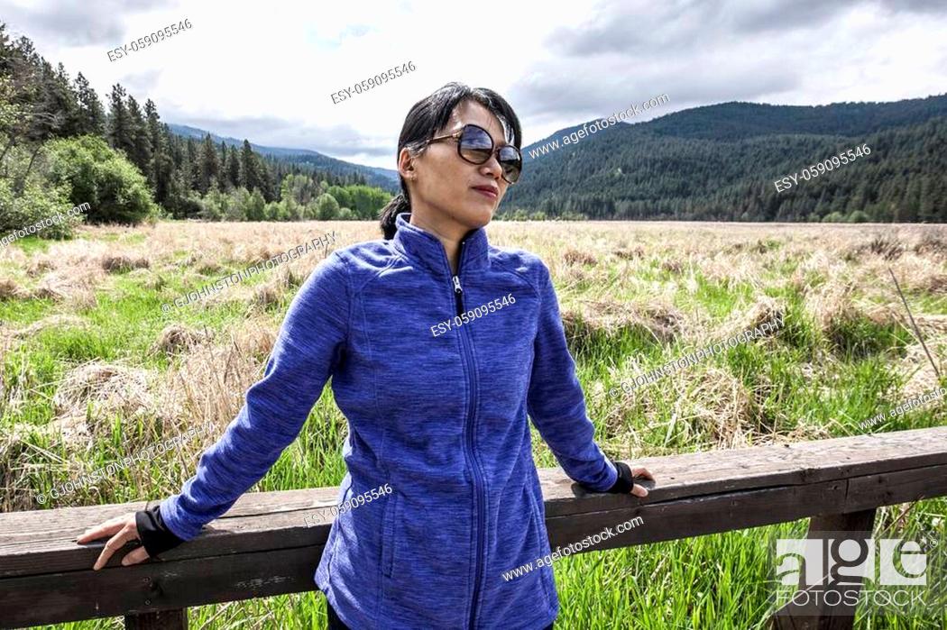 Stock Photo: An Asian woman leans against a railing at a park in Liberty Lake, Washington.
