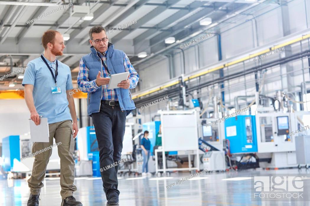 Stock Photo: Male supervisor and worker with digital tablet talking and walking in factory.