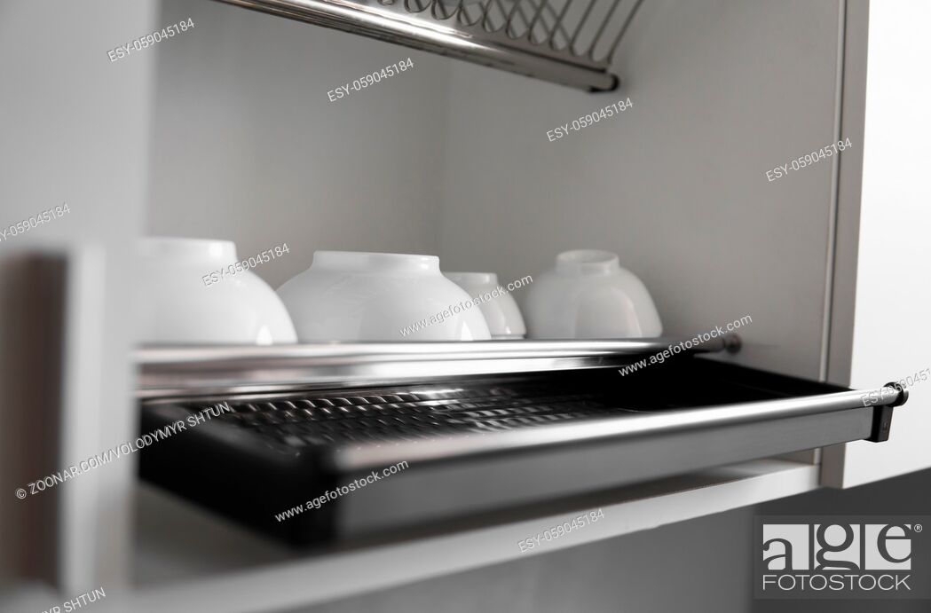 Stock Photo: Dish drying metal rack with big nice white clean plates. Traditional comfortable kitchen. Open white dish draining closet with wet dishes of glass and ceramic.