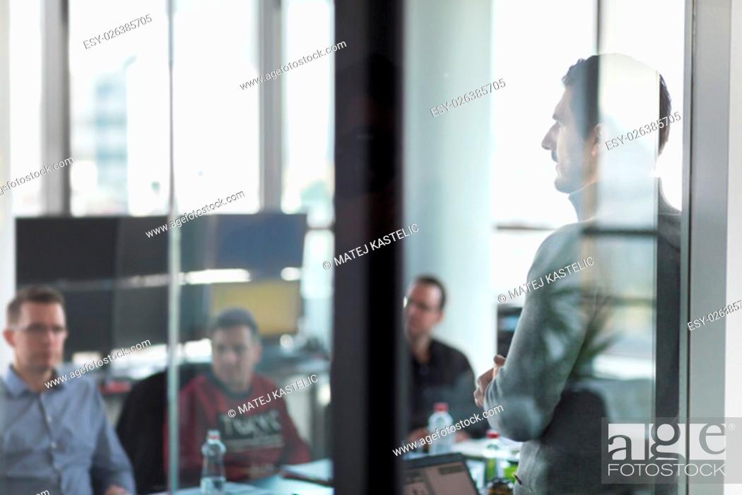 Stock Photo: Businessman making a presentation at office. Business team leader delivering a presentation to his colleagues during meeting or in-house business training.