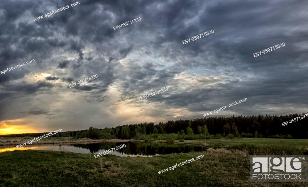 Stock Photo: Lake at sunset, coastal grass and trees. The light of the sunset above the water.