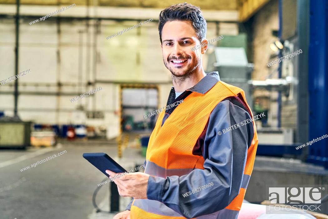 Stock Photo: Portrait of smiling man holding tablet in factory.