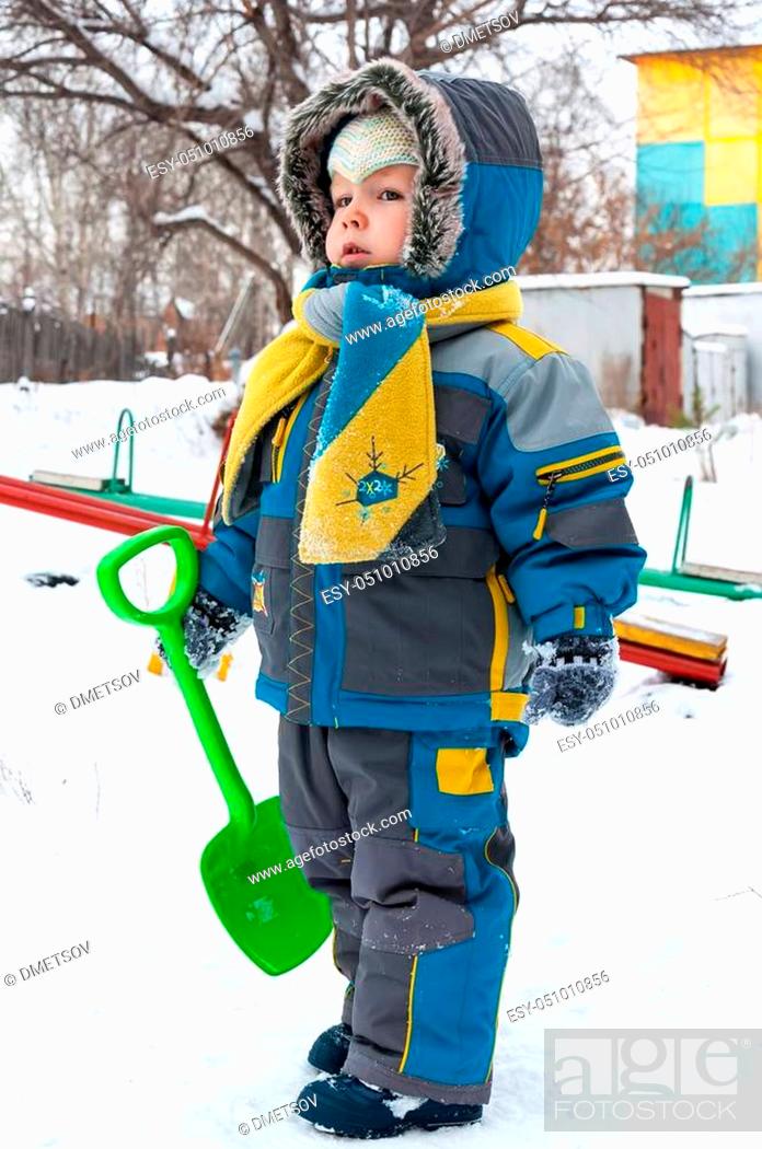 Photo de stock: Little boy playing with snow and spade. Baby playing with snow in winter outdoors. Winter vacations. Children's winter games outdoors.