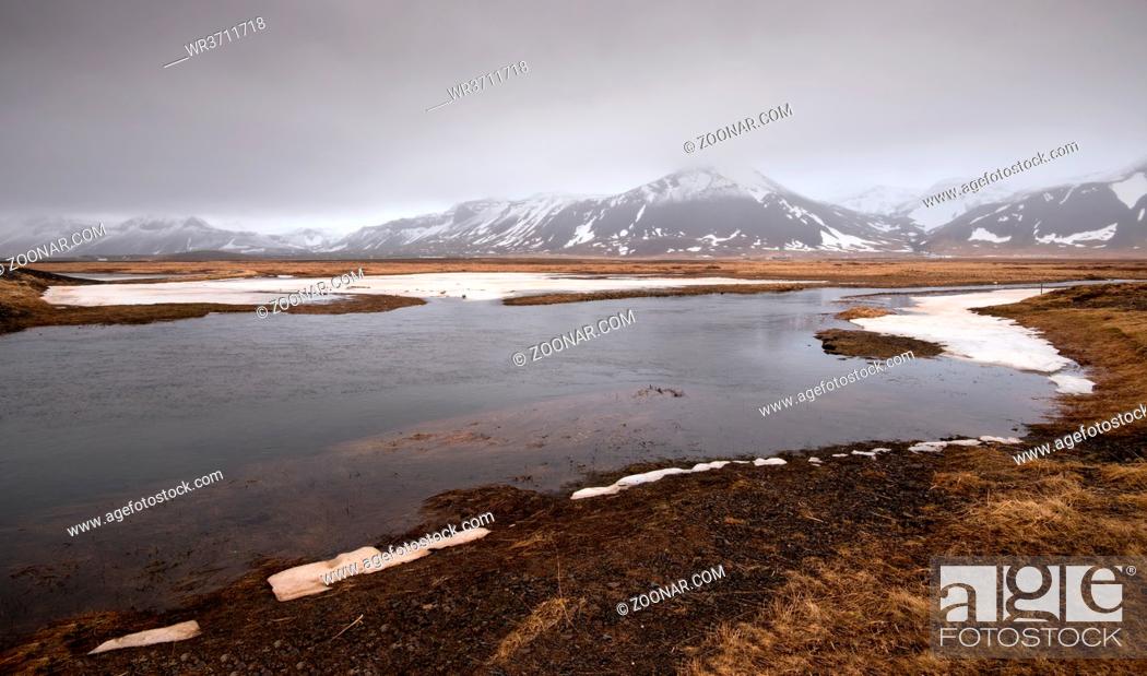 Stock Photo: Typical Icelandic dramatic landscape with frozen lake and mountains covered in snow in Iceland.