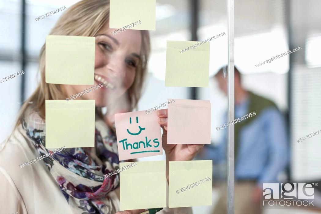 Stock Photo: Woman in office writing thanks on sticky note.