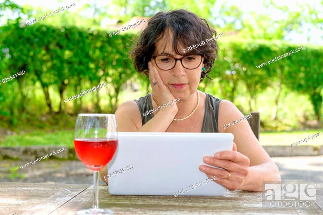 Stock Photo: a charming woman with a tablet in her garden.