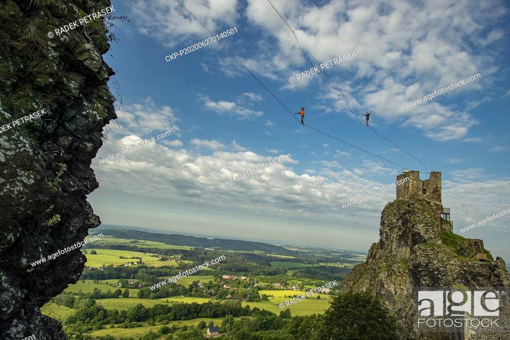 Stock Photo: Slackliners perform slacklining at height of 50 meters between two towers of the Trosky Castle, Czech Republic, on June 27, 2020.