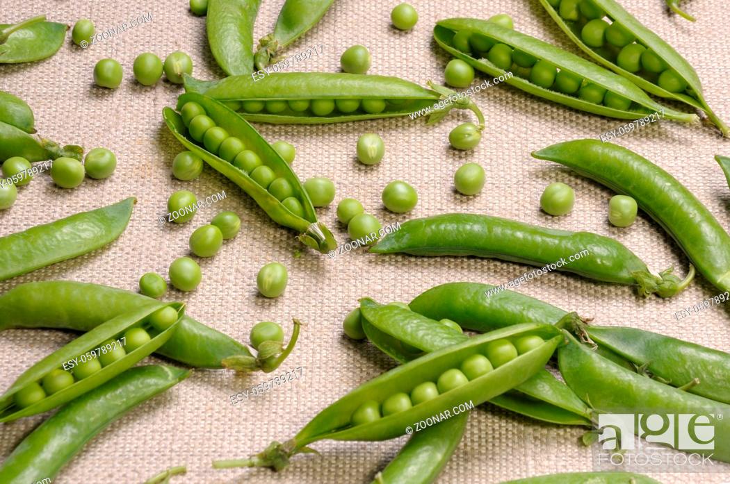 Stock Photo: Scattered pods peas and green peas on a canvas cloth.