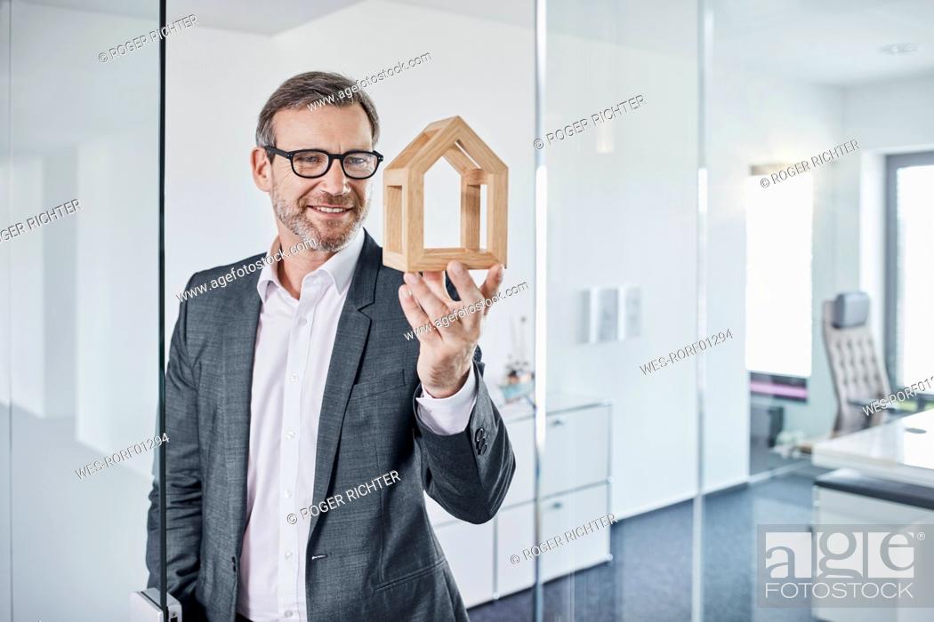 Imagen: Smiling businessman looking at architectural model in office.