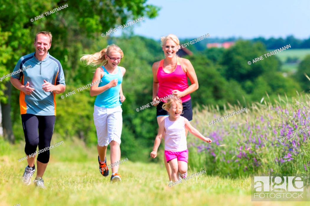 Stock Photo: Eltern und Töchter joggen gemeinsam durch den Wald.