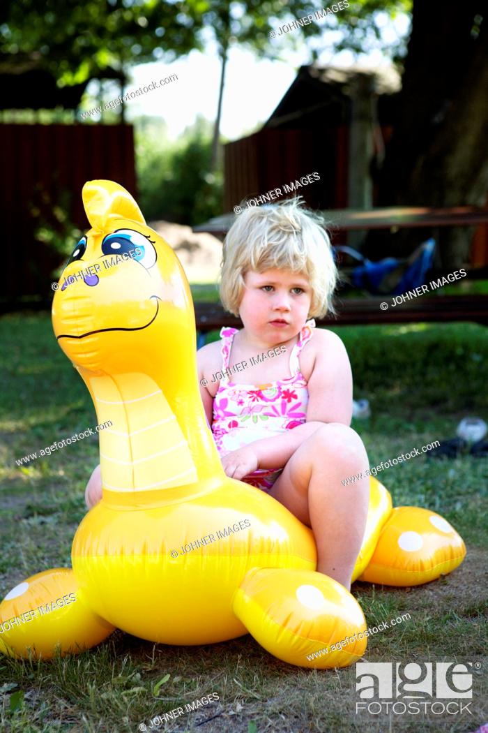 Stock Photo: Girl sitting on a toy, Sweden.
