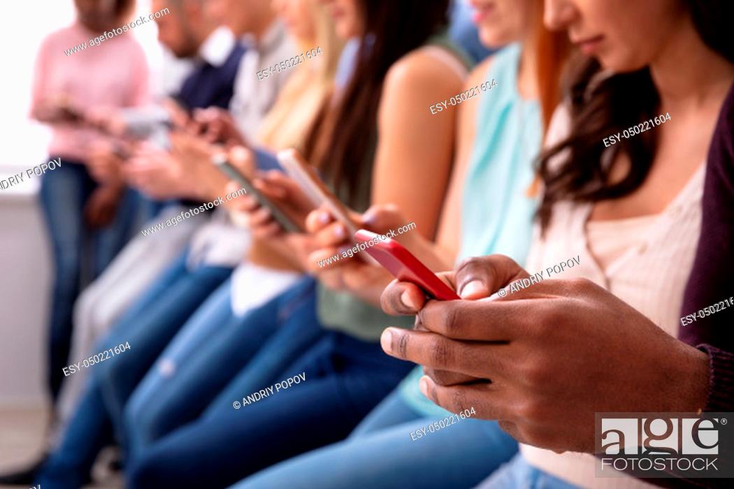 Stock Photo: Multi-ethnic Young People Leaning Near Table In Row Using Smartphone.