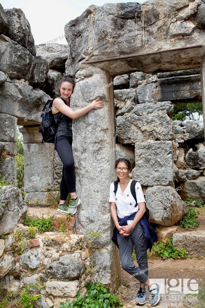Photo de stock: Female tourists stand against stone wall ruins; Cefalu, Sicily, Italy.