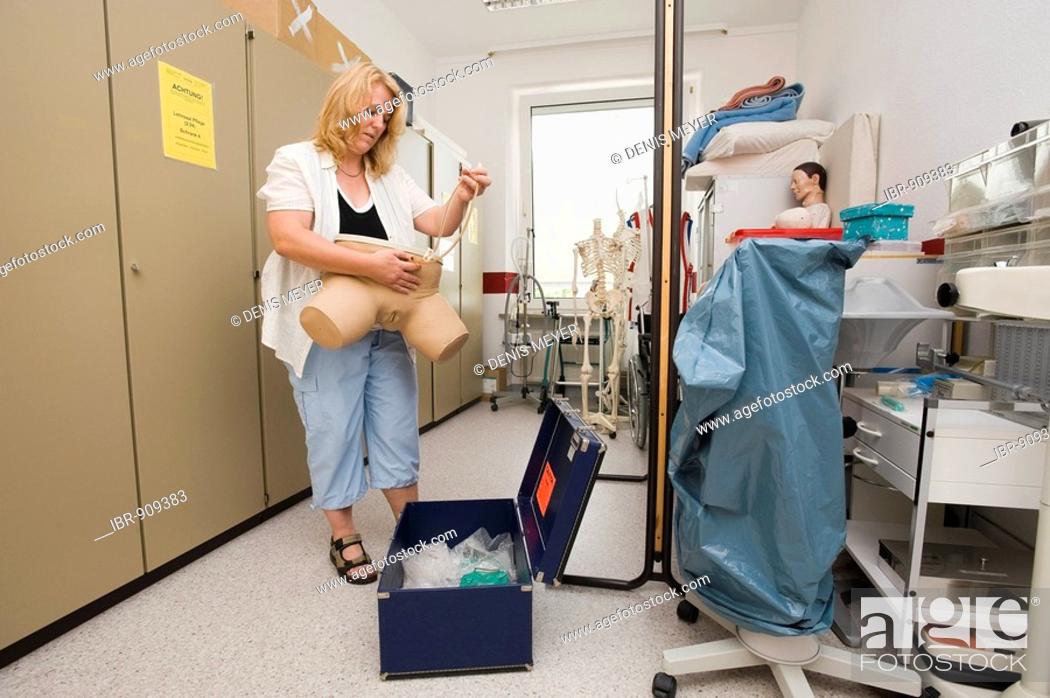 Stock Photo: Geriatric care trainer prepares a dummy for catheter training in the teaching aid storeroom.