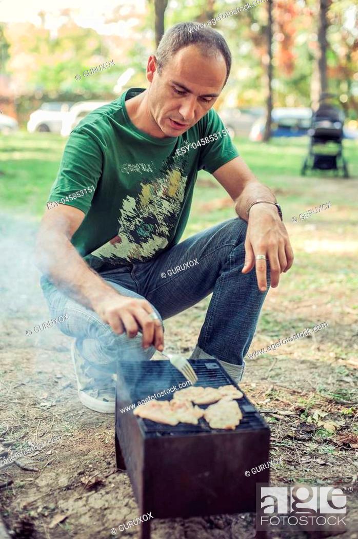 Stock Photo: Hungry man making barbecue outdoors in the park.