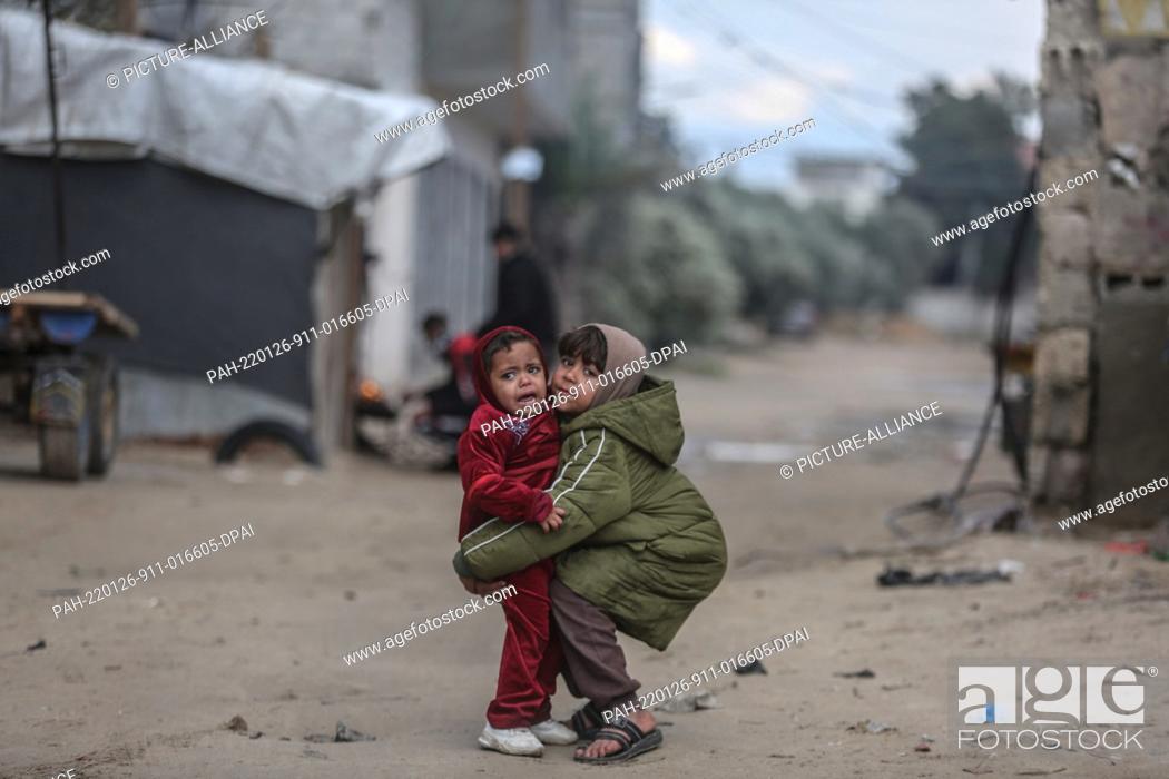 Stock Photo: 26 January 2022, Palestinian Territories, Beit Lahia: Palestinian children stand in front of their house during the cold weather of the winter season in the.