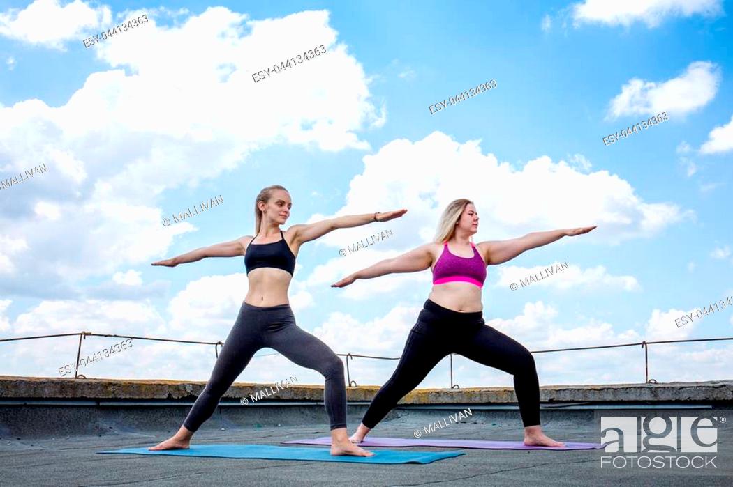 Stock Photo: Two young women doing yoga on the roof of a building.
