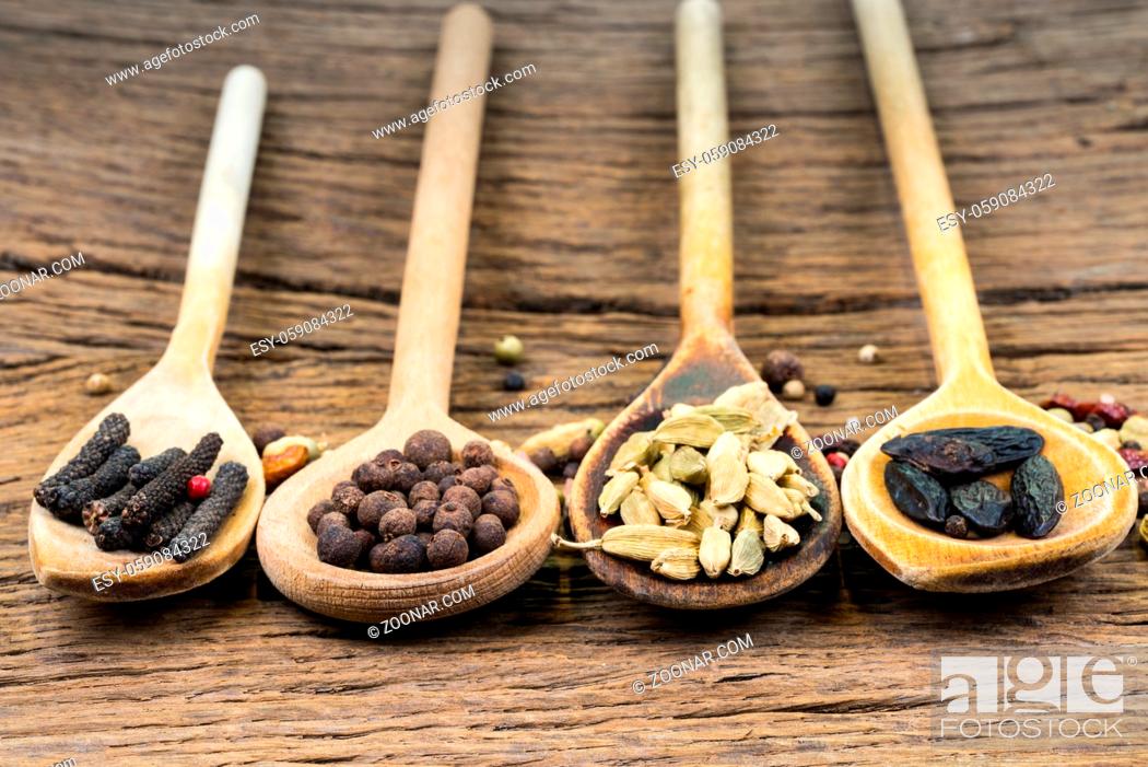 Stock Photo: Closeup of four wooden cooking spoons in a row with various exotic spices on a rustic wooden background with copy space.
