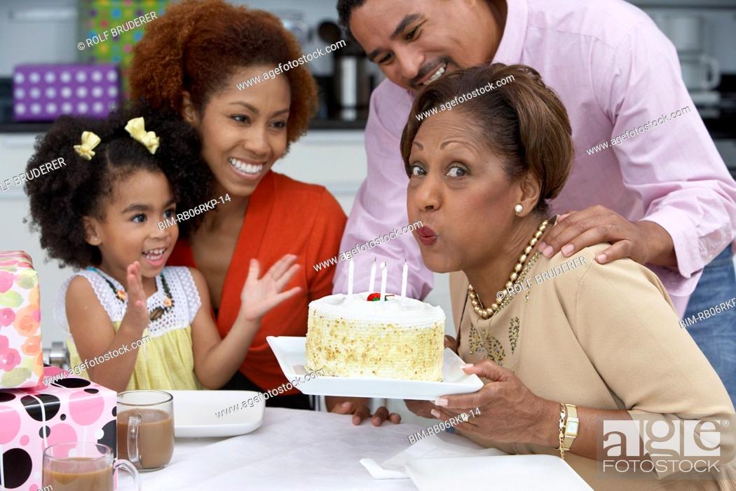 Stock Photo: Mature woman blowing out the candles on her birthday cake.