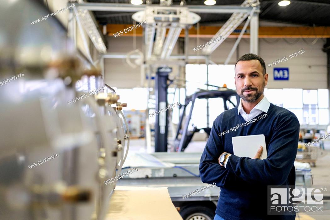 Imagen: Portrait of a confident businessman holding tablet in a factory.