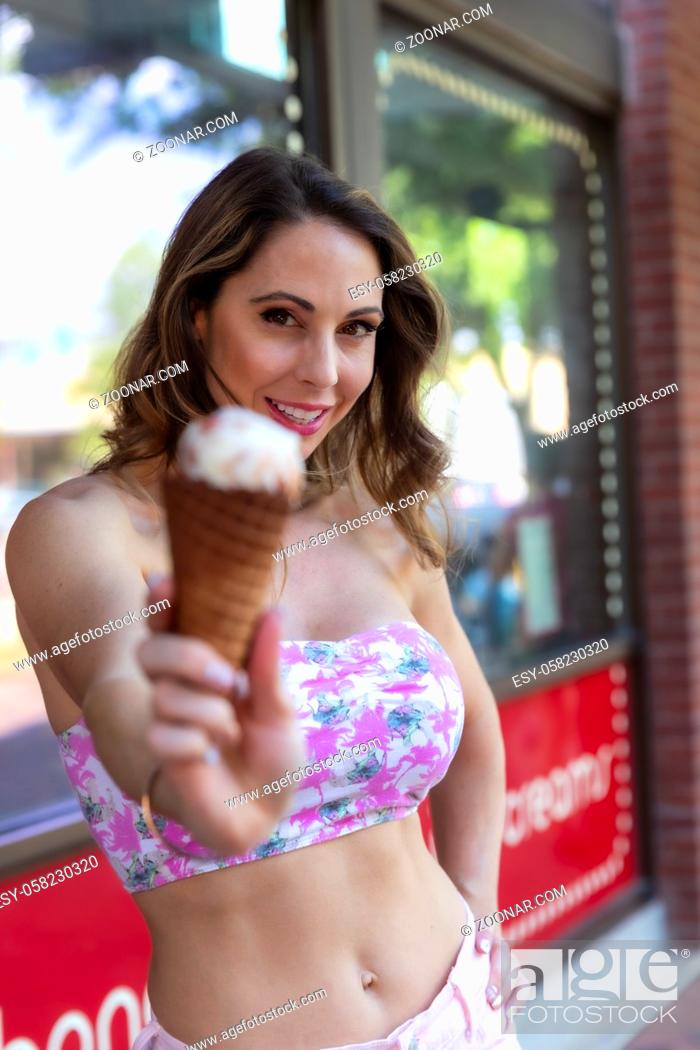 Stock Photo: A beautiful Brunette model enjoys some ice cream on a hot summers day.