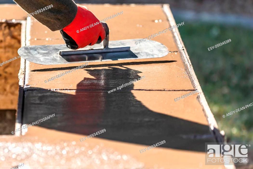 Stock Photo: Construction Worker Using Trowel On Wet Cement Forming Coping Around New Pool.