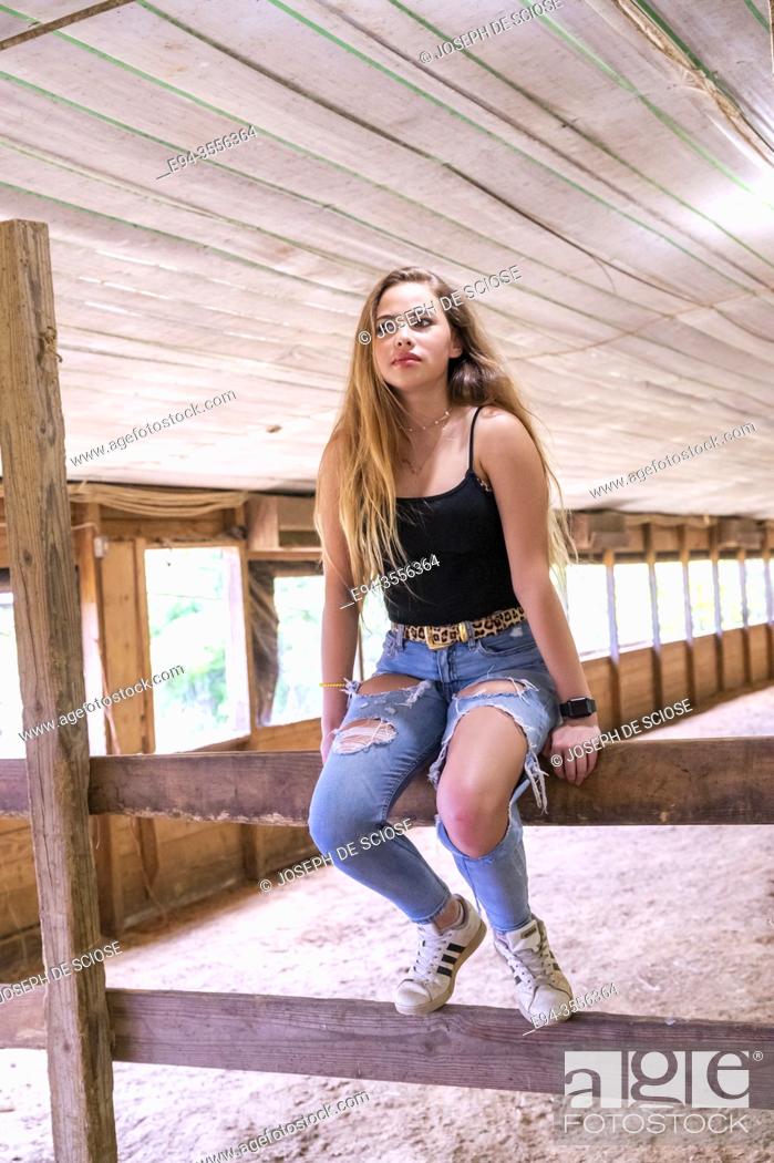 Stock Photo: A 14 year old brunette girl in a horse barn looking away from the camera.