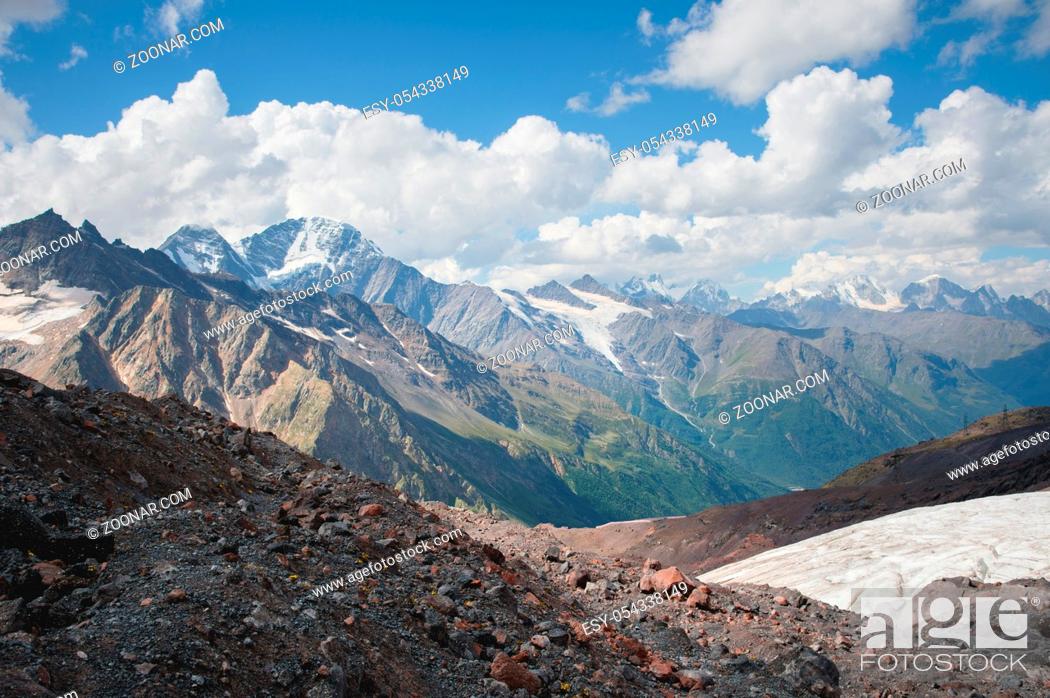Stock Photo: Mountain landscape dusty dirty volcanic slope with a cracked melting glacier against the backdrop of the Caucasus Mountains. Global warming.