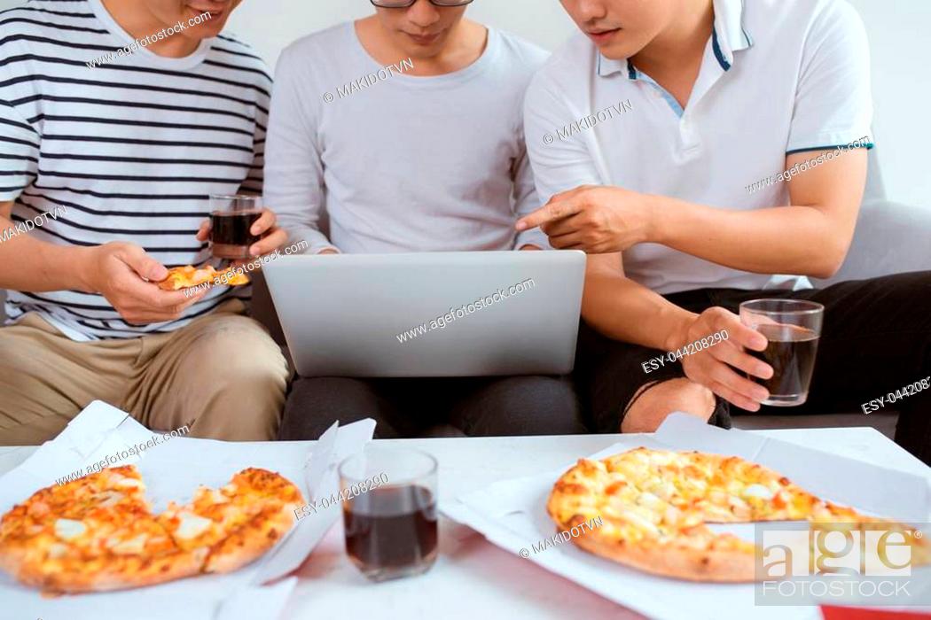 Stock Photo: Joyful friends enjoying their pizza while sitting on couch at home.