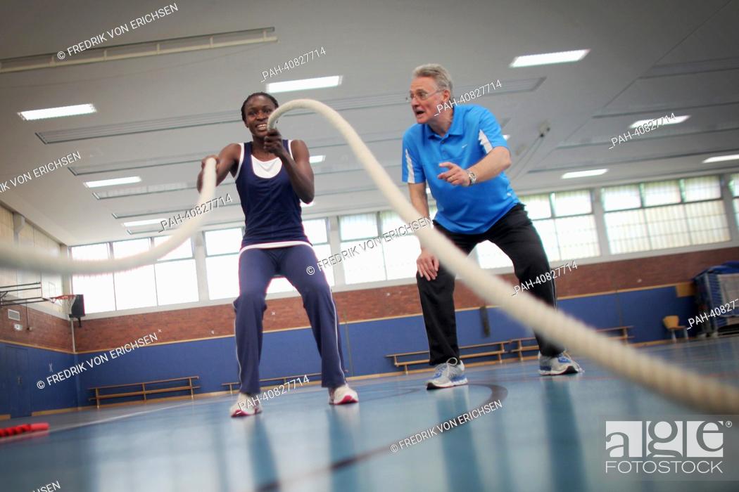 Stock Photo: Head coach Werner Steinmann instructs Pauline Compaore from Burkina Faso how to jump rope in subject of sport at the Johannes Gutenberg University in Mainz.