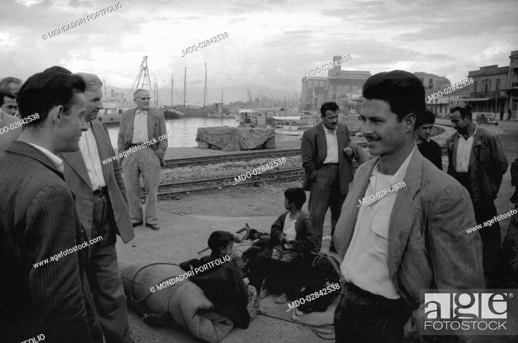 Stock Photo: Men chatting in a harbour. Greece, November 1958.