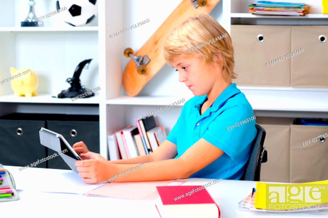 Stock Photo: blond boy using tablet computer in his room.