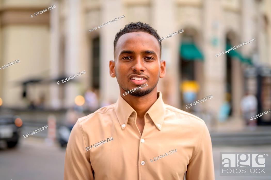 Stock Photo: Portrait of handsome black young African businessman wearing casual clothes outdoors in city.