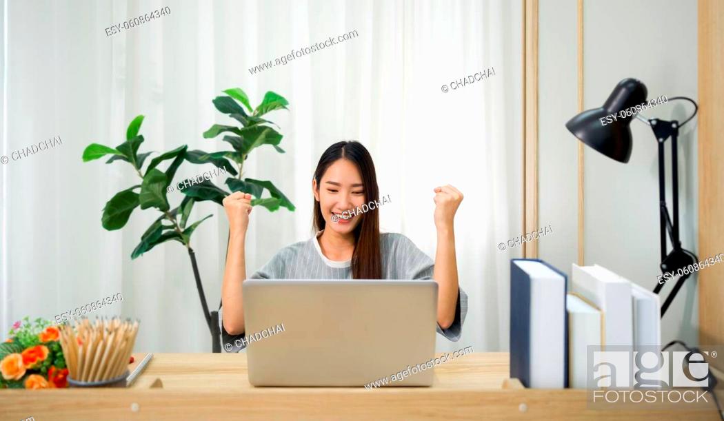 Stock Photo: An Asian woman rejoiced by raising her fists with a smile. After receiving an email notifying the results of the university entrance examination.
